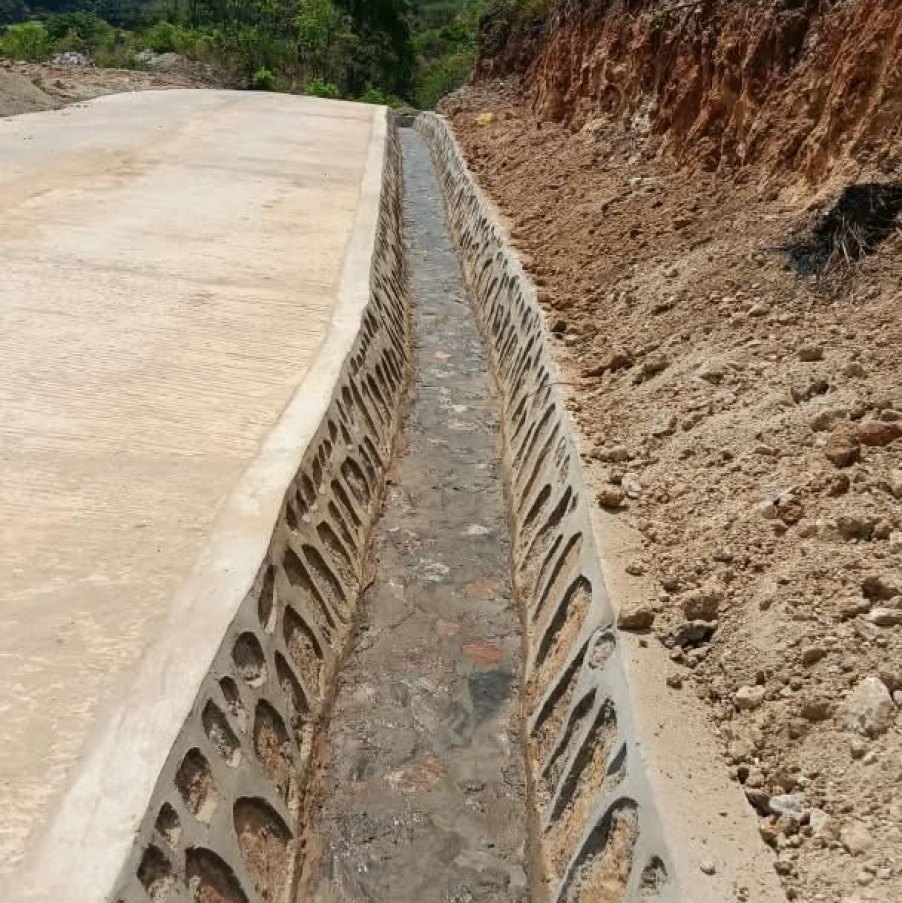 A concrete-lined drainage channel constructed beside a road